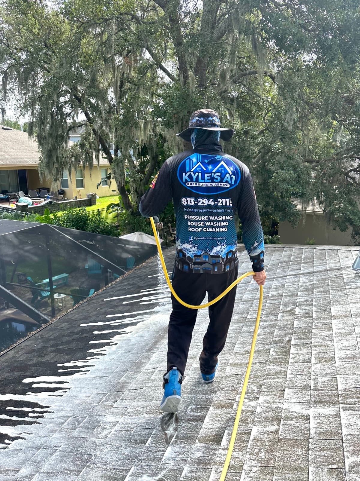 Technician applying soft wash solution to roof