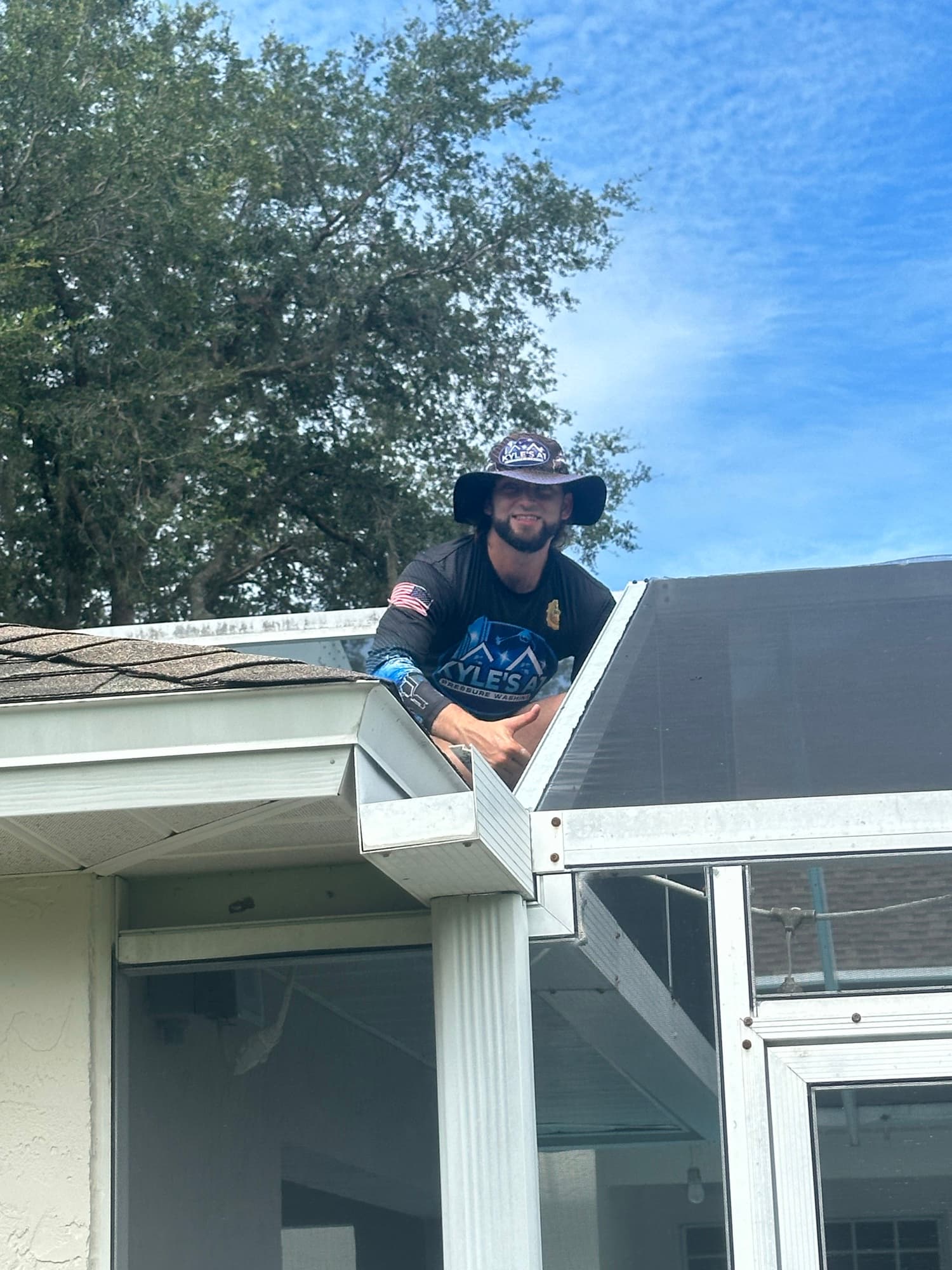 Technician cleaning gutters on roof in Valrico