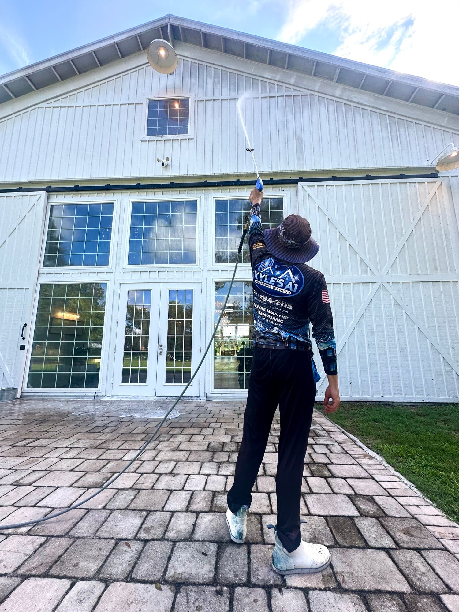 Technician soft washing large commercial building exterior