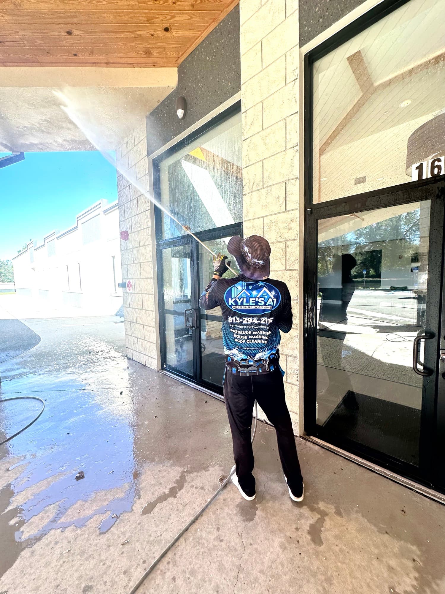 Worker pressure washing commercial storefront